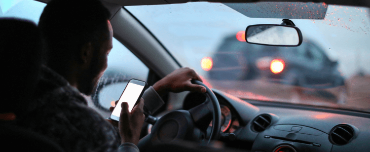 Man recklessly driving with his phone in his hand